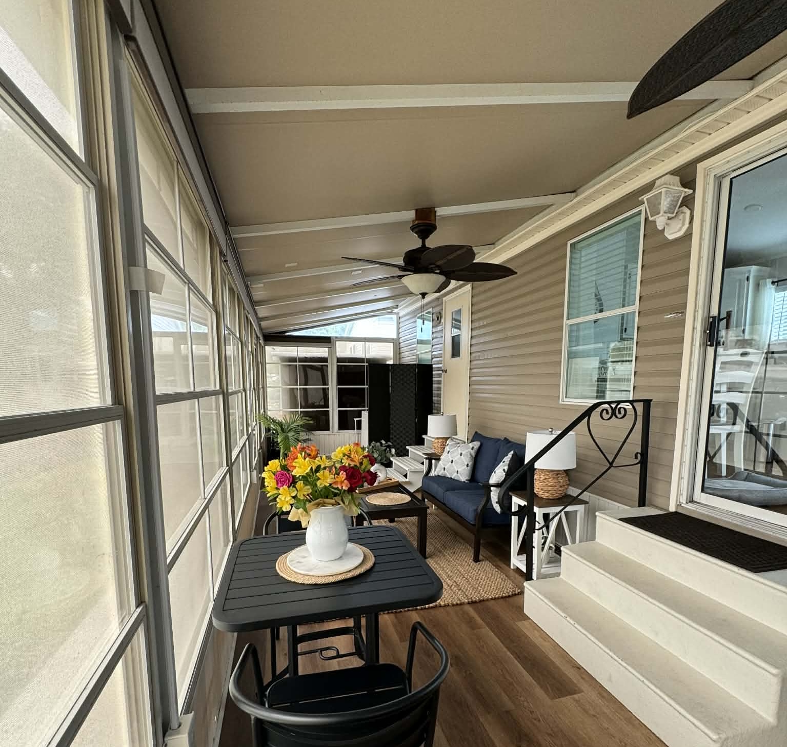 Dining table and lounge area along the screened lanai, with steps leading into the home