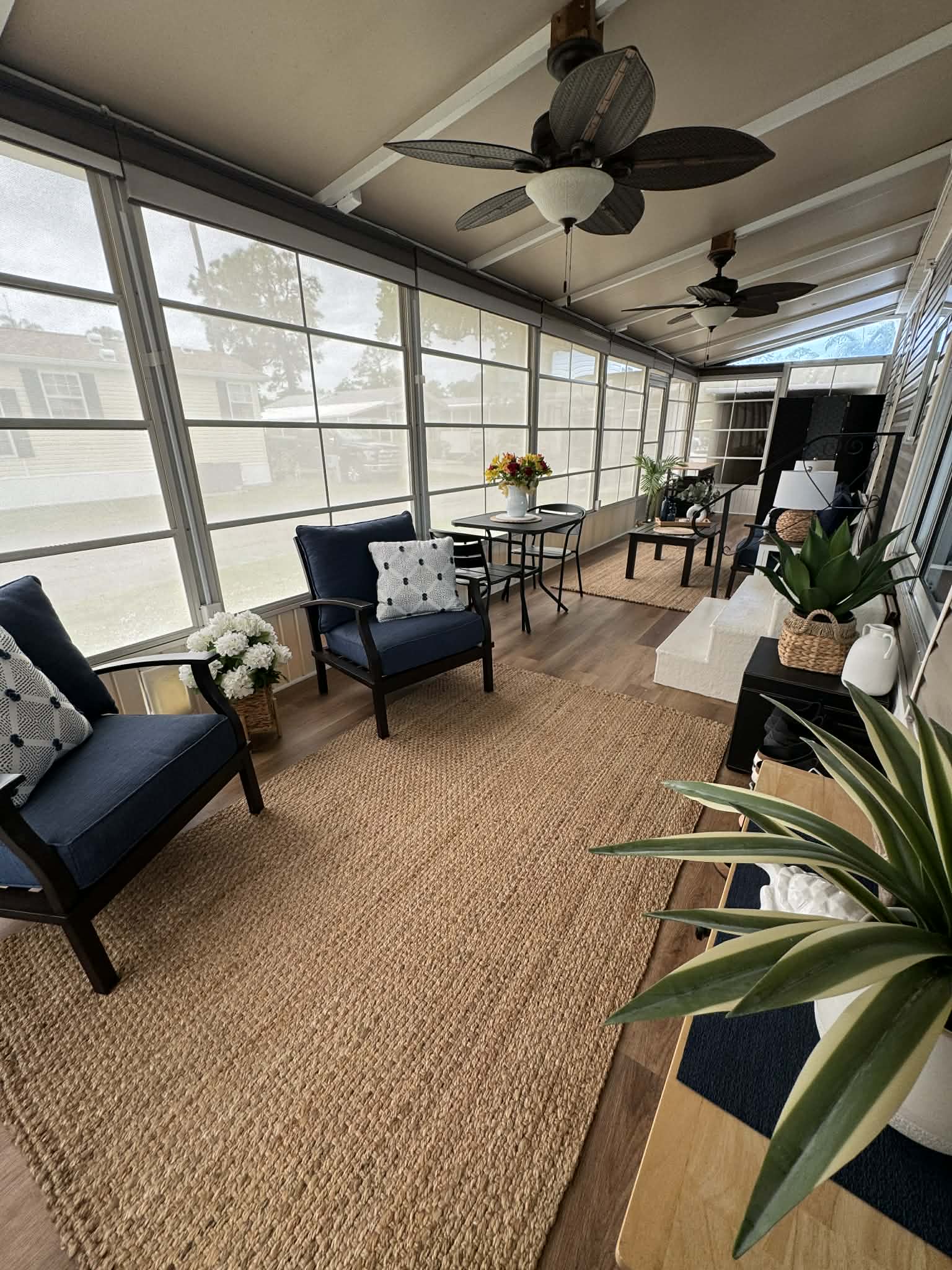 Spacious screened lanai at Home 1165, with navy seating, a dining nook, ceiling fans, and natural light