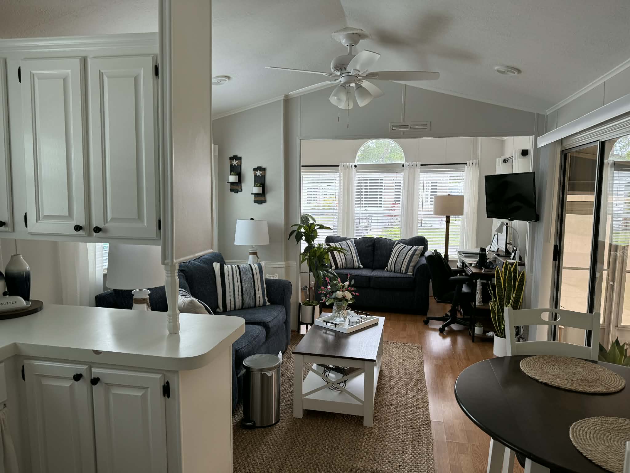 Bright living room with navy sofas, an office nook, and adjoining kitchen and dining area